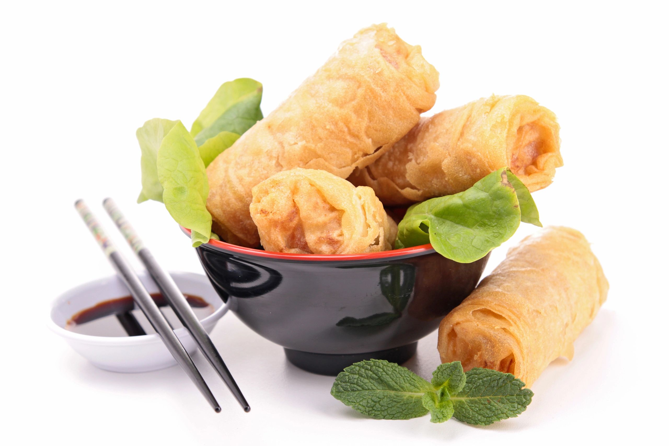Fried spring rolls with dipping sauce in a black bowl.