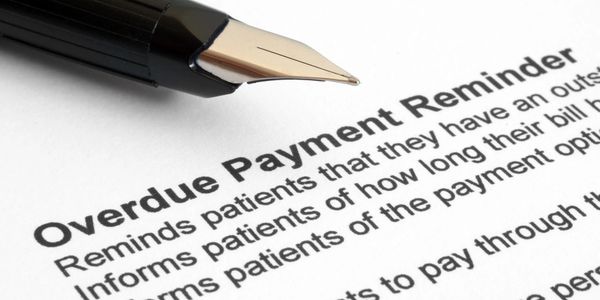 Close-up of a fountain pen on an overdue payment reminder document.