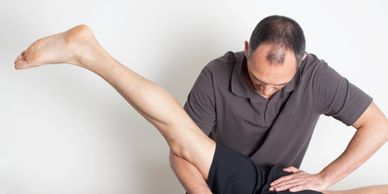 Therapist assists patient with leg stretch during physical therapy session.