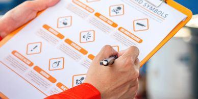 Person holding clipboard with hazard symbols and explanations.
