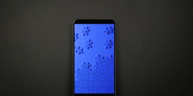 Smartphone displaying a blue jigsaw puzzle in progress on the screen.