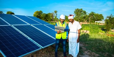 Technician and farmer discussing solar panels in a field.