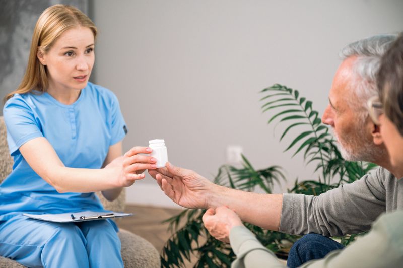 Selective focus on bottle with pills holding by nurse in blue medical uniform. Family doctor recommend supplements or antibiotic to elderly patients at home appointment. Prescriptions, treatment plan
