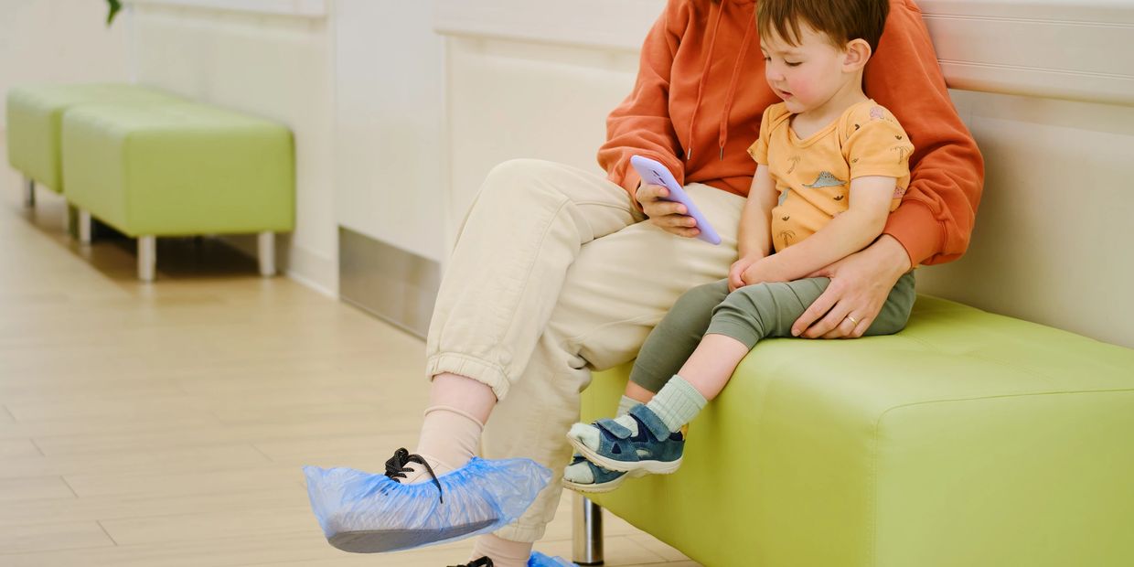 Adult and child sitting on a green bench.