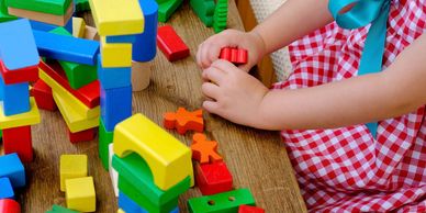 Child playing with colorful wooden building blocks on a table.