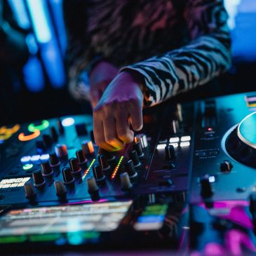 DJ adjusting sound levels on a mixer in a dimly lit club.