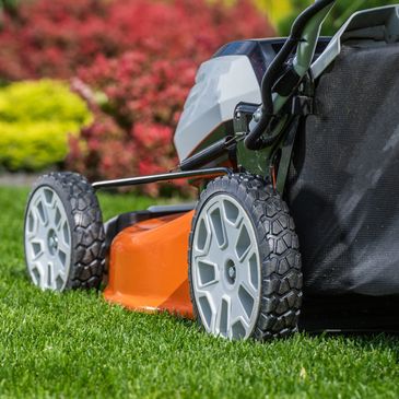 Close-up of an orange lawn mower on freshly cut green grass.