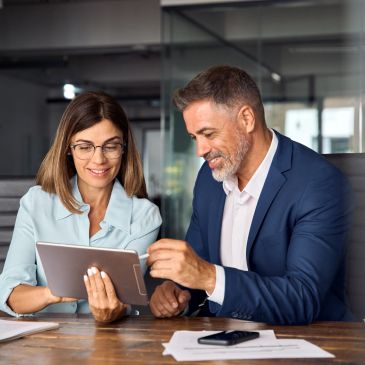 Two professionals reviewing documents on a tablet.
