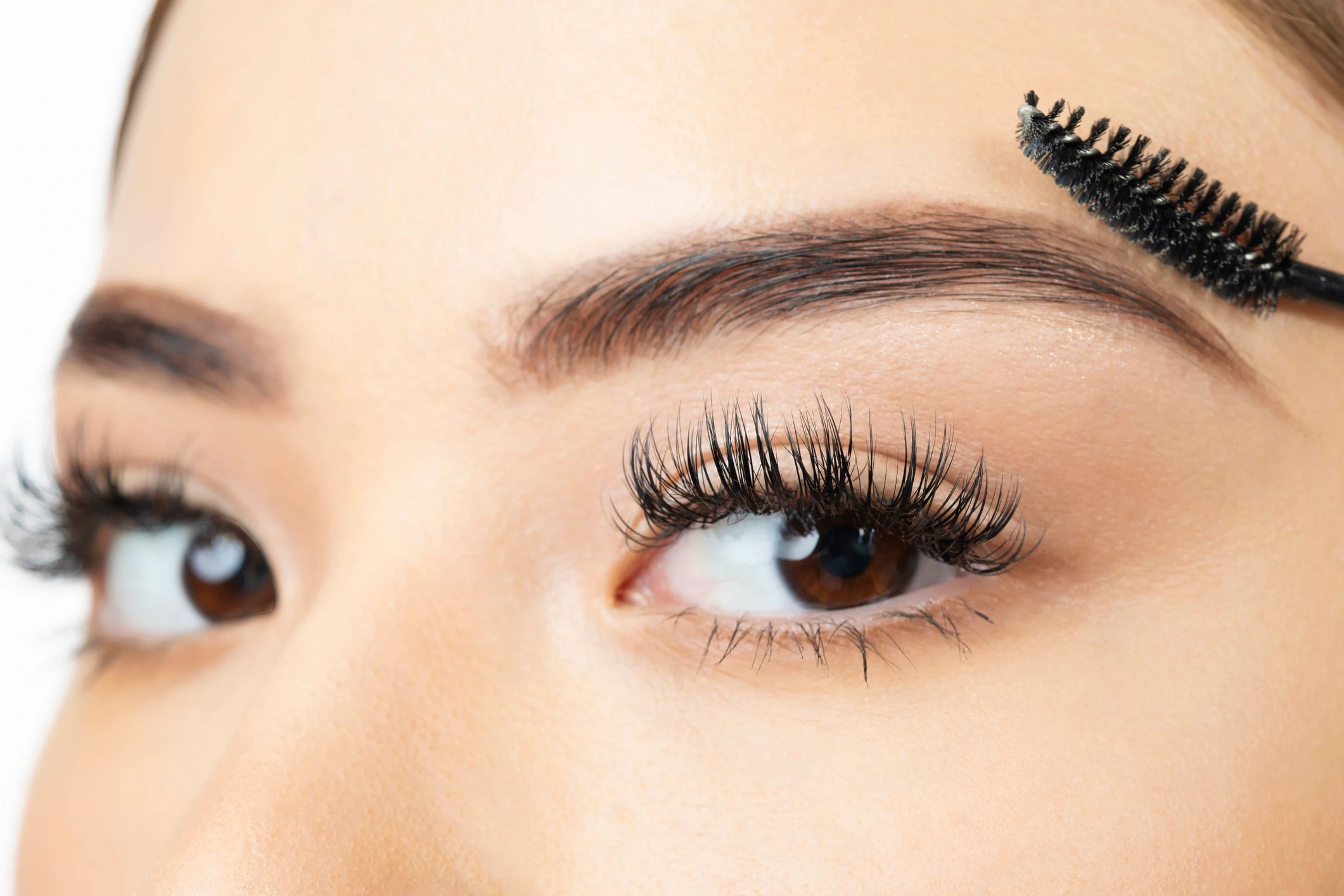Person grooming eyebrows with spoolie brush.