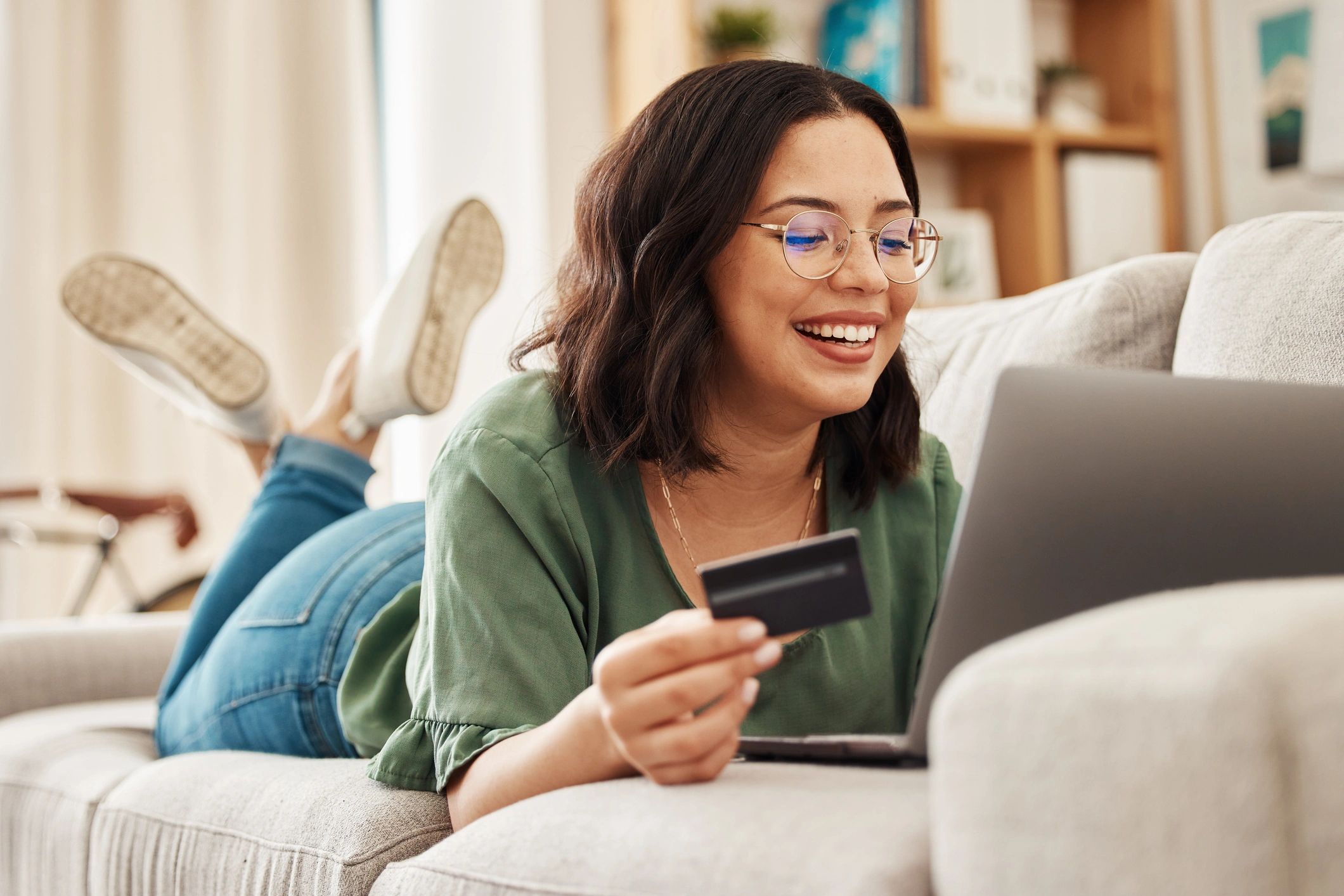 Happy woman shopping online with a credit card and laptop.