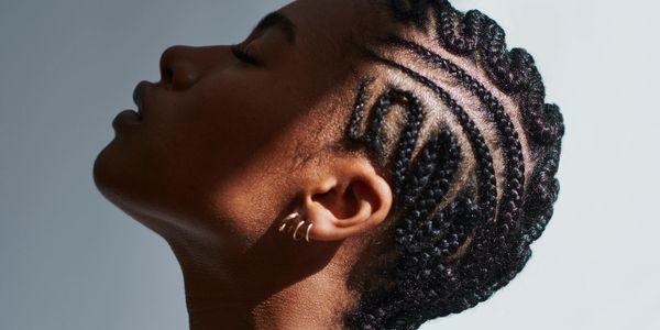 Profile of a woman with intricate braided hairstyle and closed eyes.