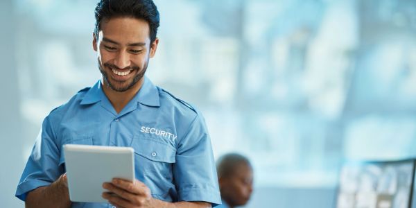 Smiling security guard using a tablet.