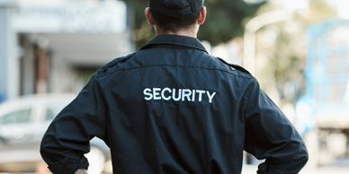 Security guard standing outdoors with hands on hips.