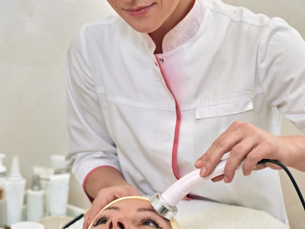 A skincare professional performs a facial treatment using a handheld device.