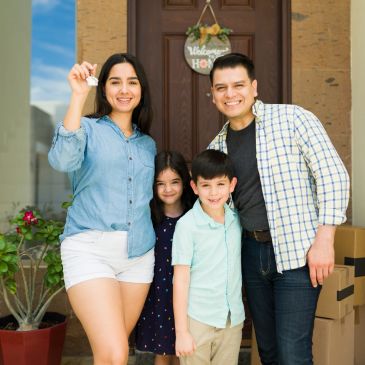 Happy family holding keys in front of their new home.