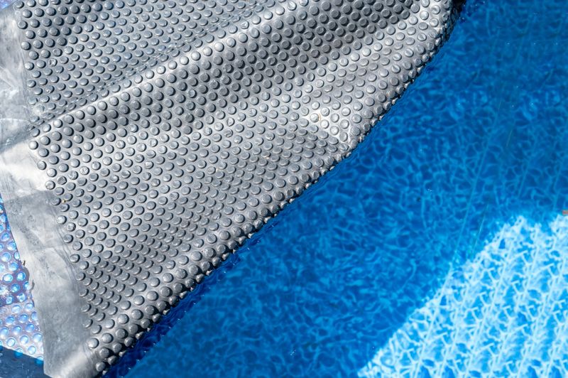 Retractable floating pool cover to keep out leaves and keep in heat being pulled back from water. . High quality photo