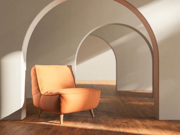 Orange cushioned chair in a sunlit room with arched doorways and wooden floors.
