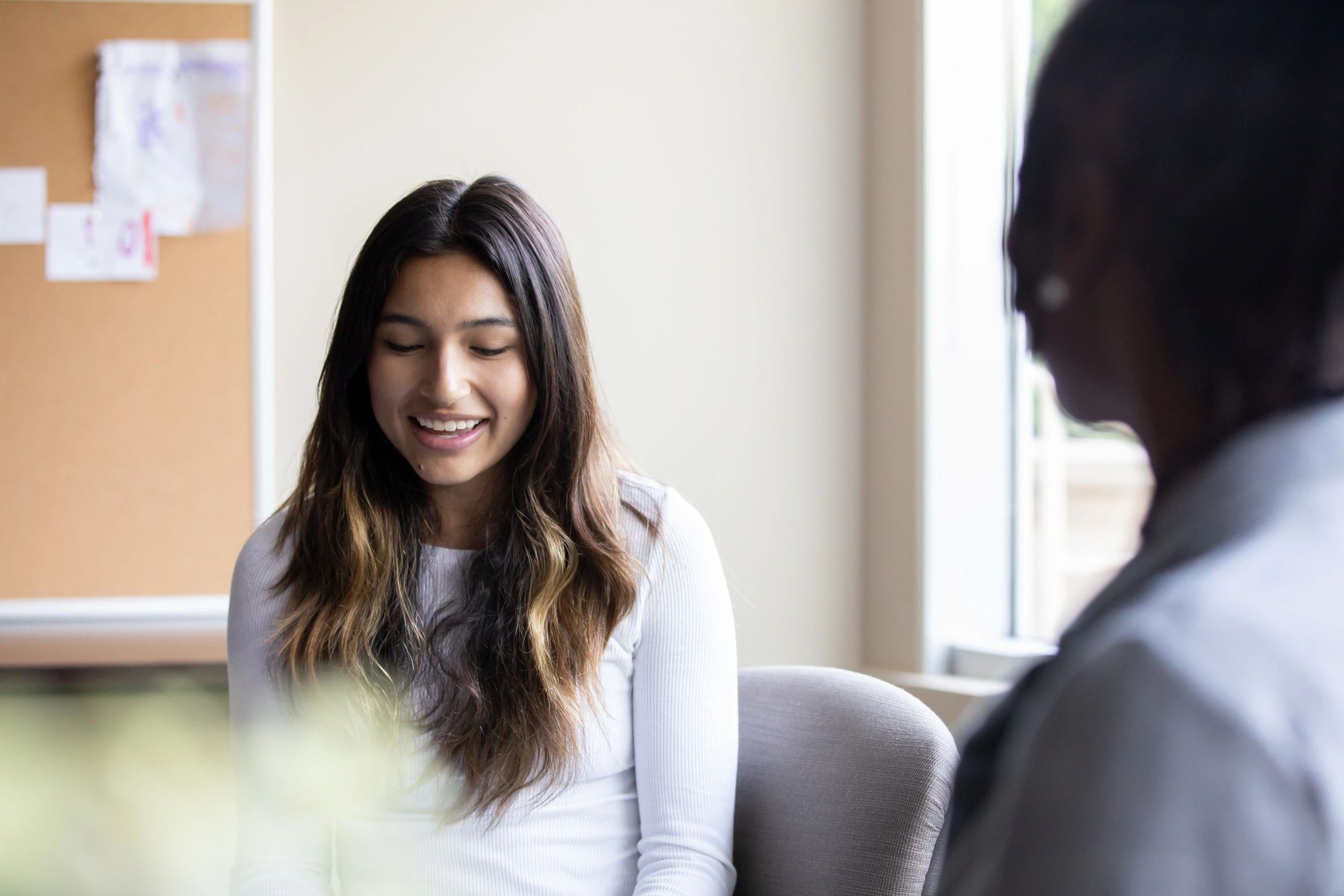 Young woman smiling in conversation in a cozy room.