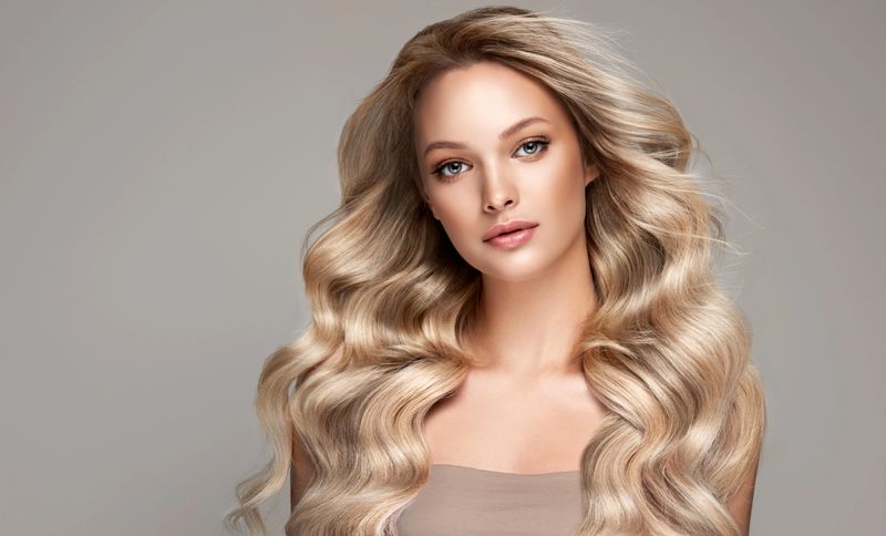 Portrait of beautifully looking young blond haired woman dressed in a delicate evening makeup.Perfect model straightly gazing by kind tender look at viewer. Beauty elegance hairstyling.