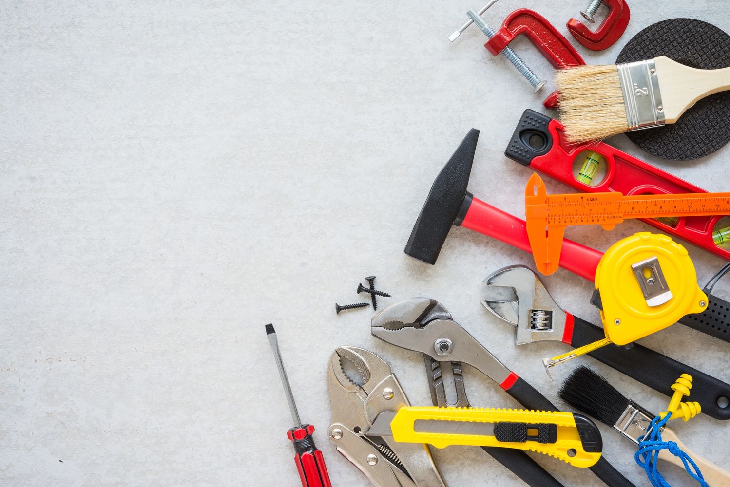 Various hand tools laid out on a light surface.