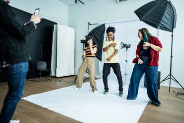 Three friends having fun and dancing in a photo studio while one takes their picture.