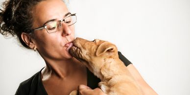 A woman affectionately kissing a puppy.