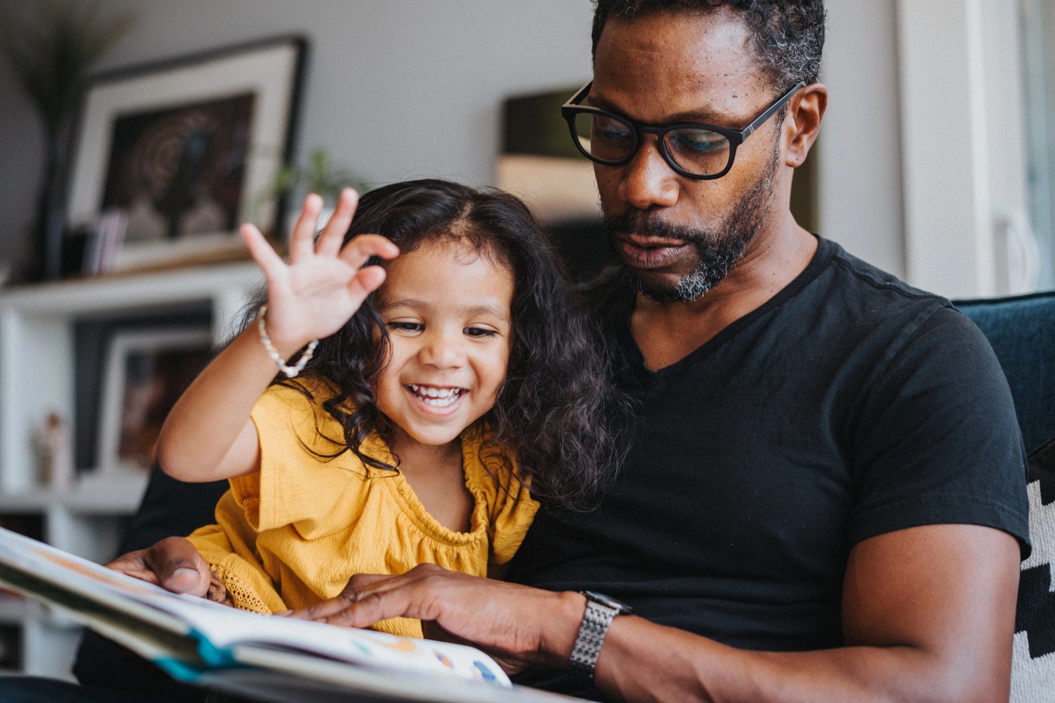 Father and daughter enjoying a children's picture book together, celebrating the joy of reading.