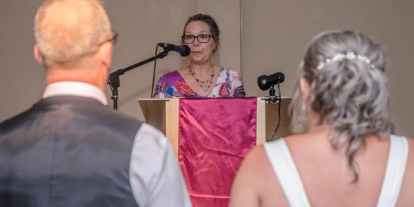 Woman speaking at a wedding ceremony podium.