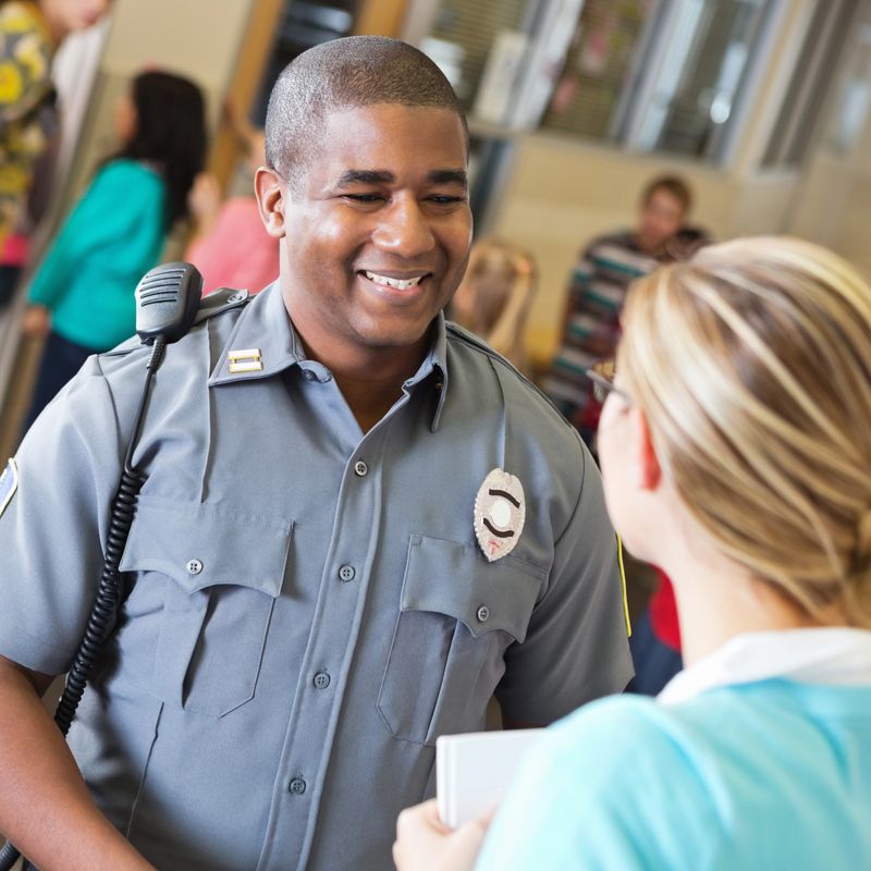 Friendly police officer talking with school teacher after safety demonstration