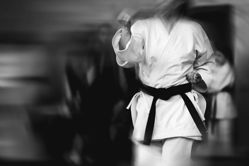 Abstract black and white karate background. The concept of expressionism and motion blur with a barely visible silhouette of an athlete in a white kimano.