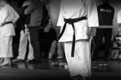 Group practicing martial arts in white uniforms with various belt colors.