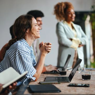 Smiling woman at a meeting with colleagues.