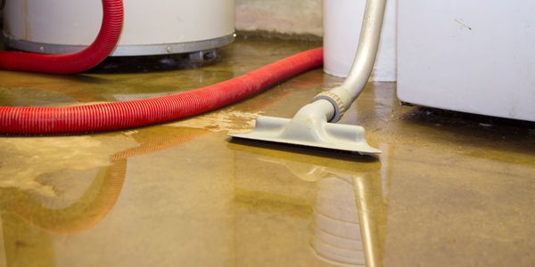 A vacuum hose is used to clean up water on a flooded floor.