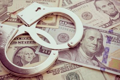 Handcuffs on various US dollar bills.