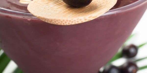 A wooden spoon resting on a bowl filled with acai.
