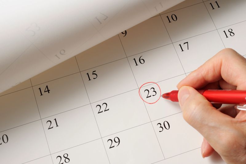 Writing a date on calendar by red pen.