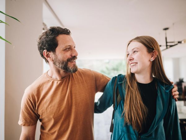 Father and daughter smiling and hugging indoors.