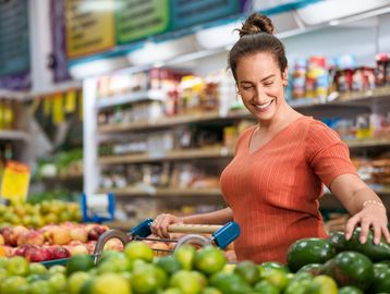 Happy woman shopping for fresh fruits in a grocery store.
