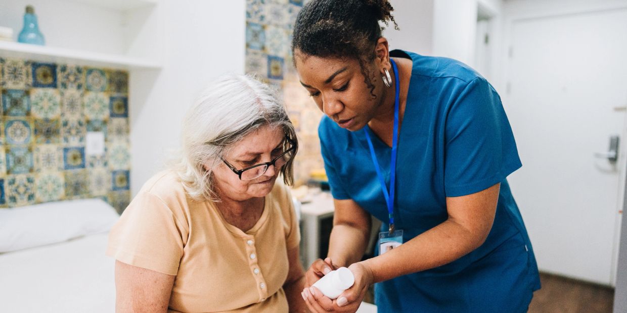 Nurse assisting elderly woman with medication.