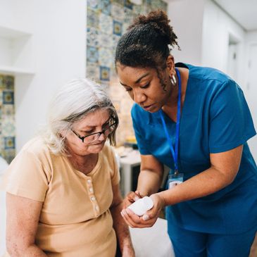 Caregiver explaining medication to an elderly woman in a home setting.