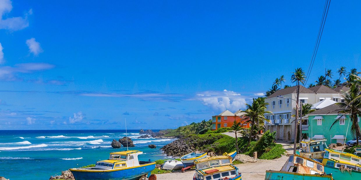 Colorful boats and houses by the tropical coast under a clear blue sky.