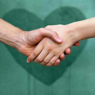 Two hands shaking with a heart shape in the background.