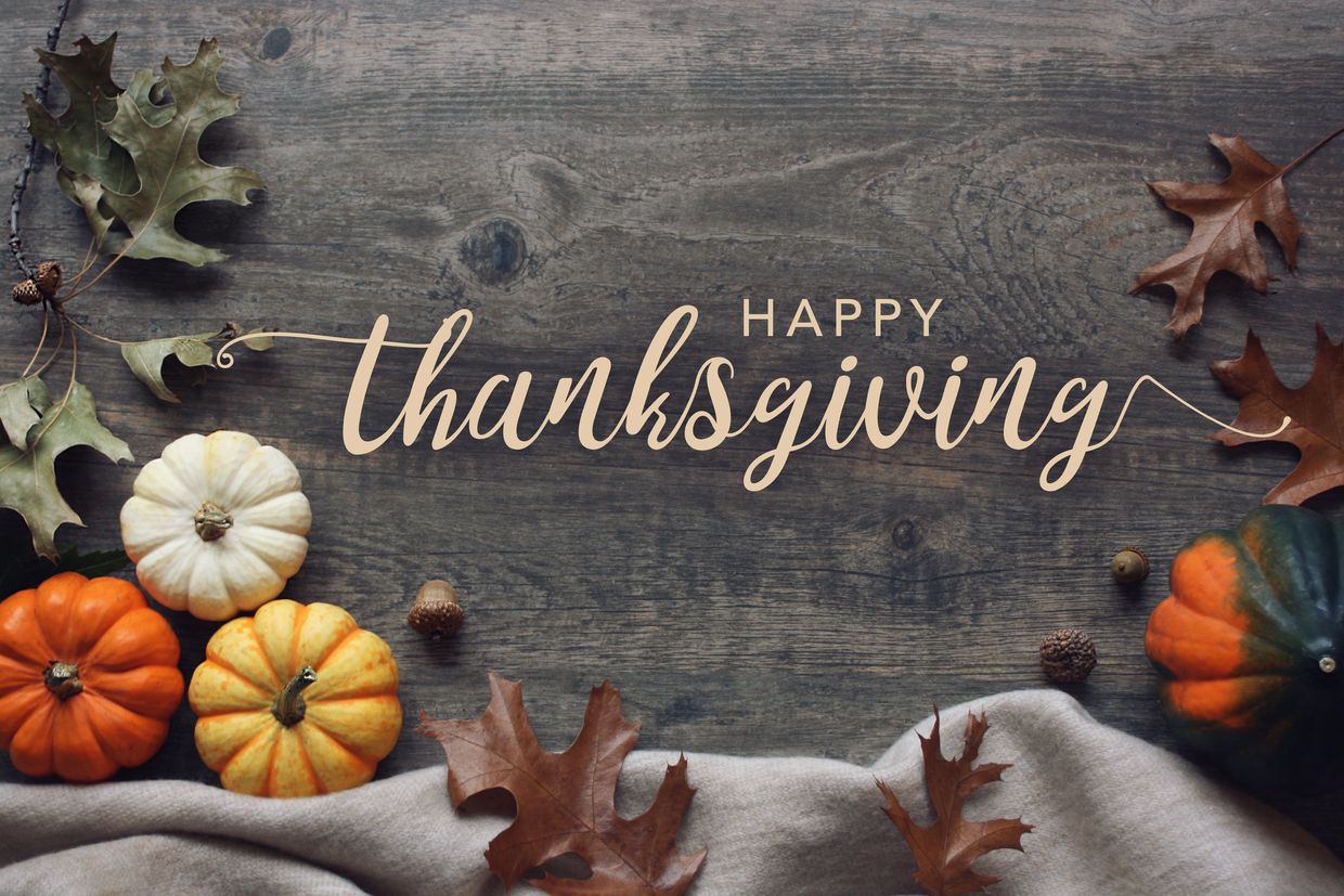 Rustic Thanksgiving greeting with pumpkins and autumn leaves on wood.