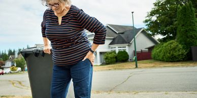 alt="Woman pulling trash can"