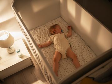 A baby sleeps peacefully in a crib with a pacifier.