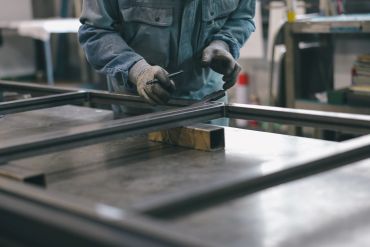 Worker handling metal frames in a workshop.