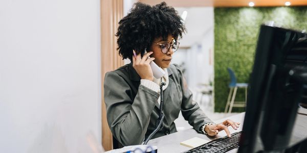 Woman talking on the phone while using a computer.