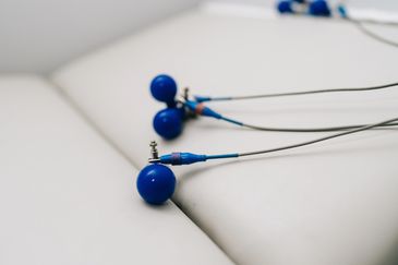 Blue wired earbuds on a white surface.