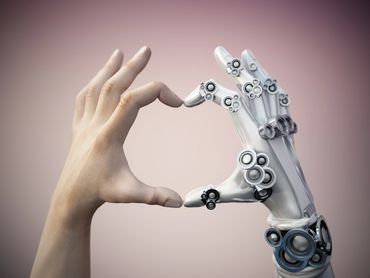 Human and robotic hands forming a heart shape together.