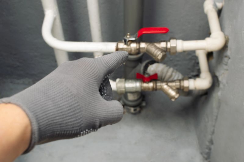 Plumber pointing at pipes on gray concrete wall, providing professional advice. Could be used for sites about home repairs, maintenance, construction services.